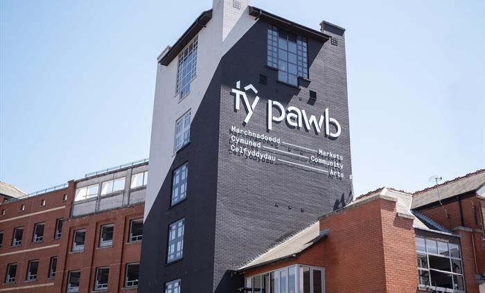 External view of the Tŷ Pawb building, featuring the main tower the Tŷ Pawb logo.